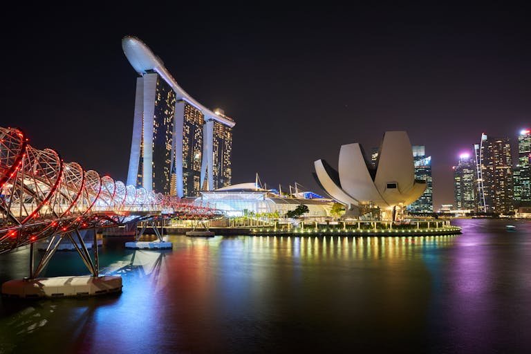 Marina Bay Sands and Helix Bridge lit up at night over the water in Singapore